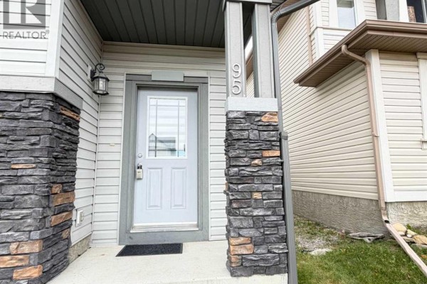 Close-up of the front entrance with a white door, frosted glass, and grey stone-clad pillars with the house number 65. - 95 Panora Close Nw, Calgary