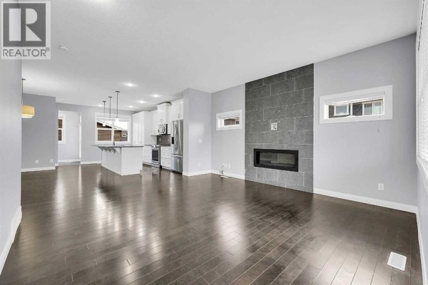 Spacious living area with dark hardwood floors and a view towards the open-concept kitchen. - 95 Redstone Park Ne, Calgary