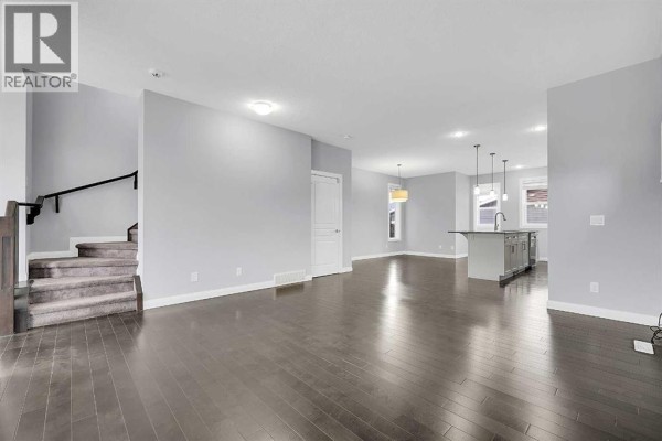 Staircase leading upstairs from the main living area, with a view of the open kitchen island. - 95 Redstone Park Ne, Calgary