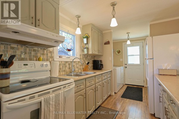 Kitchen with light grey cabinets, white appliances, and a tiled backsplash. - 95 Shannon Boulevard, South Huron