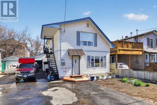 Side view of a white house showing exterior stairs leading to a second-floor balcony. - 95 Ste Cecile Street, Ottawa