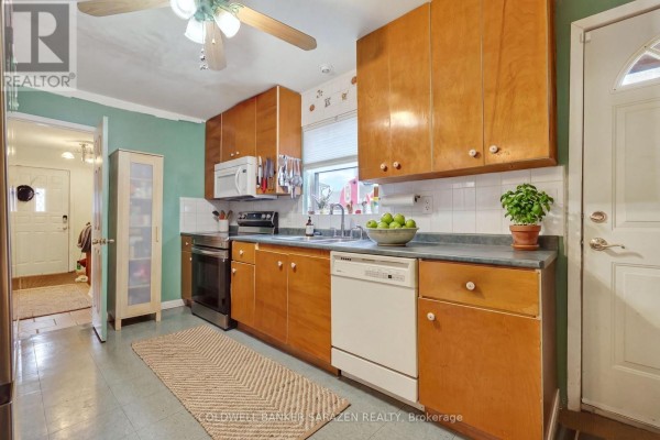 Kitchen with light wood cabinets, white appliances, and green walls. - 95 Ste Cecile Street, Ottawa