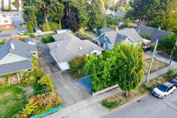 Aerial view of a single-story house and neighboring properties on a tree-lined street. - 950 Mcdonald St, Duncan