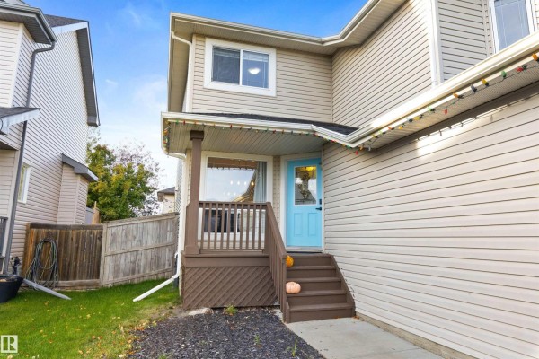 Side view of the house showing the blue front door and wooden steps. - 9506 83 Av, Morinville