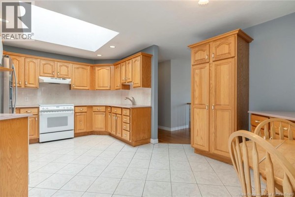 Kitchen with light wood cabinets, white appliances, tiled floor, and a skylight overhead. - 951 Ryan Street, Moncton