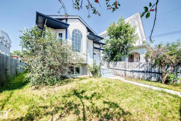 Front exterior of a white house with a pitched roof, large arched window, and blue trim, viewed from a lower angle. - 9518 106 Av Nw, Edmonton
