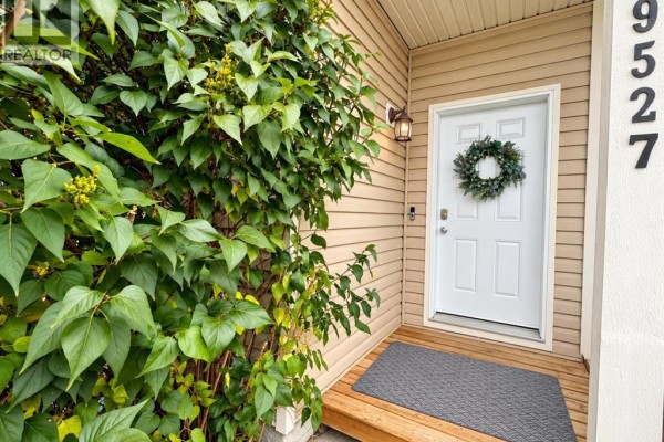 Close-up of the front door with a green wreath and a grey doormat. - 9527 93 Street, Wembley