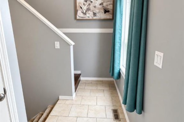 Interior hallway with beige tiled floor, grey walls, and a staircase leading up. - 9527 93 Street, Wembley