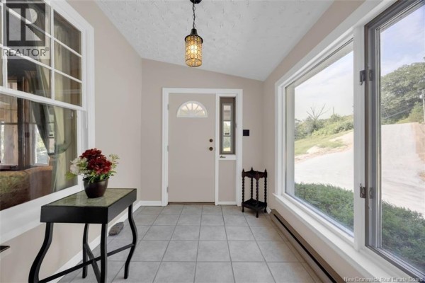 Interior view of a bright entryway with light beige walls, tiled floor, and large windows. - 9531 Route 102, Morrisdale