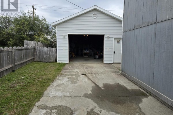 View of the open detached garage with tools, storage, and a canoe hanging from the ceiling. - 954 Cashin Crescent, Labrador City