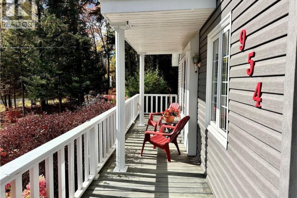 Porch with two red chairs and a white railing on a grey house. - 954 Main Street, Grand Sault/grand Falls