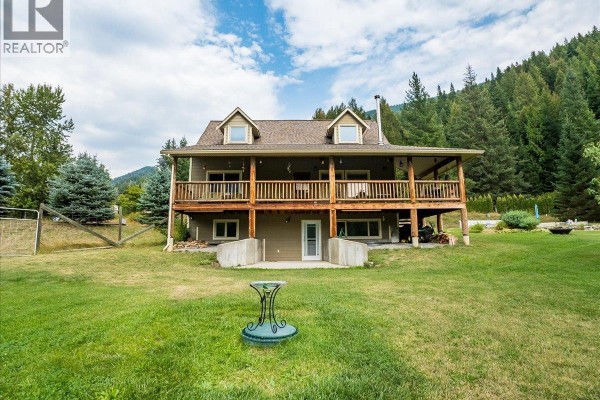 Aerial view of a two-story house and detached garage on a wooded property with driveway. - 955 Cedar Brae Road, Glade