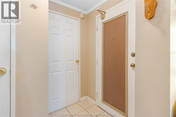Interior hallway with two white doors and beige walls. - 955 Grand Avenue West Unit# 208, Chatham