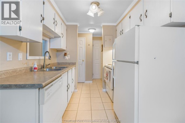 Galley kitchen with white cabinets, countertops, and appliances. - 955 Grand Avenue West Unit# 208, Chatham
