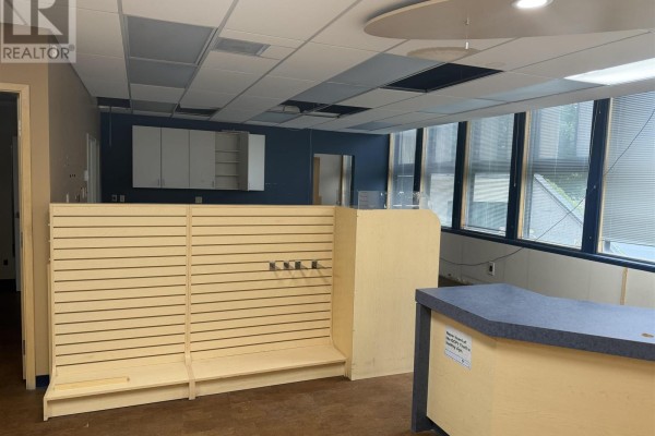 Empty commercial space with slatwall shelving units, a reception desk, and large windows with blinds. - 955 Queen St E # 145, Sault Ste  Marie