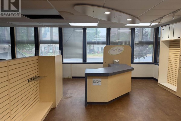 Interior of a commercial space featuring slatwall shelves, a reception counter, and multiple windows overlooking the street. - 955 Queen St E # 145, Sault Ste  Marie