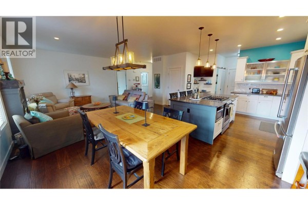 Living and dining area with light wood furniture, fireplace, and teal kitchen accents. - 956 Copper Point Way, Invermere