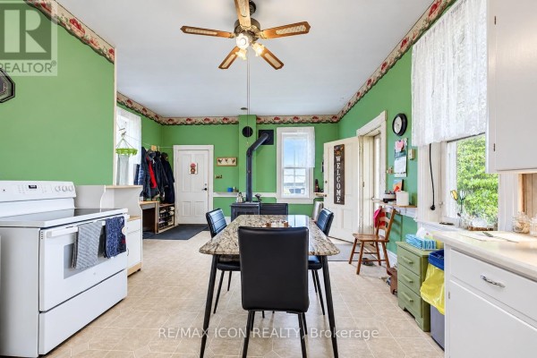 Kitchen and dining area with green walls, a wood stove, and a marble-topped dining table. - 9562 Wellington Rd 16 Road, Wellington North