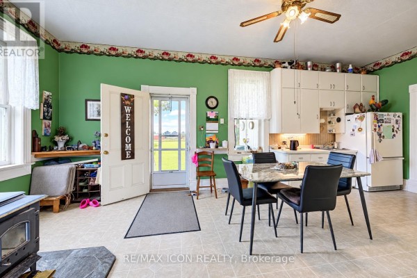 Kitchen with white cabinets, a refrigerator, and a dining table, overlooking a field. - 9562 Wellington Rd 16 Road, Wellington North