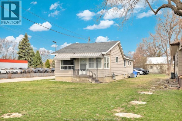 Side view of a beige house with a gray roof and green lawn. - 9572 Tecumseh Road, Windsor