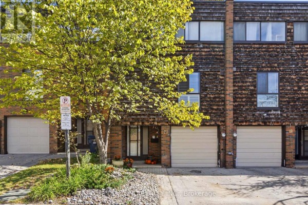 Front view of a townhouse complex showing multiple units with garages and wood siding. - 41 Carl Shepway, Toronto