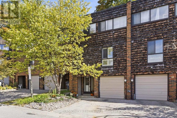 A row of townhouses with wood and brick exteriors, including individual garages and front entrances. - 41 Carl Shepway, Toronto