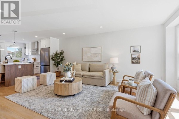 Living room featuring a neutral sofa, round coffee table, and two armchairs with a view of the kitchen. - 96 - 51 Sholto Drive, London South