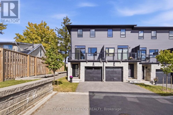 Street view of a townhouse complex with grey siding and stone accents. - 96 - 51 Sparrow Avenue, Cambridge