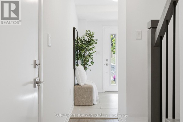Interior hallway with white walls, tile floor, and a glass-paneled door. - 96 - 51 Sparrow Avenue, Cambridge