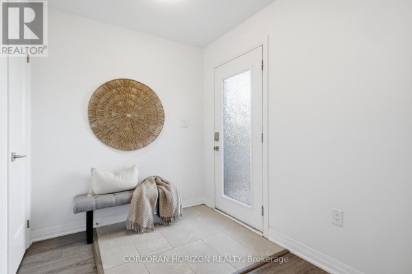 Entryway with white walls, tiled floor, bench, and decorative wall hanging. - 96 - 51 Sparrow Avenue, Cambridge