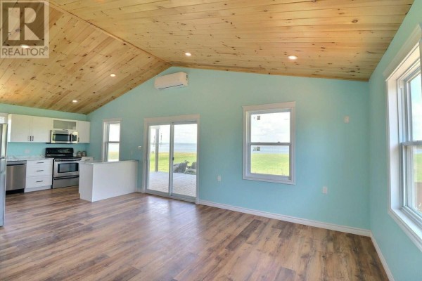 Living area with light blue walls, vaulted wood ceiling, and a sliding glass door to the outside. - 96 Arr Beach Lane, Beach Point