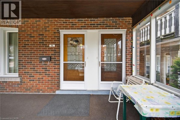Front porch entrance featuring two wooden doors with decorative glass panels and a small table. - 96 Barnesdale Boulevard, Hamilton