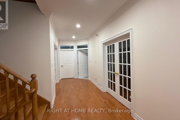 Hallway with hardwood floors, white walls, white trim, a staircase with wooden banister, and glass French doors. - 96 Bradgate Drive, Markham