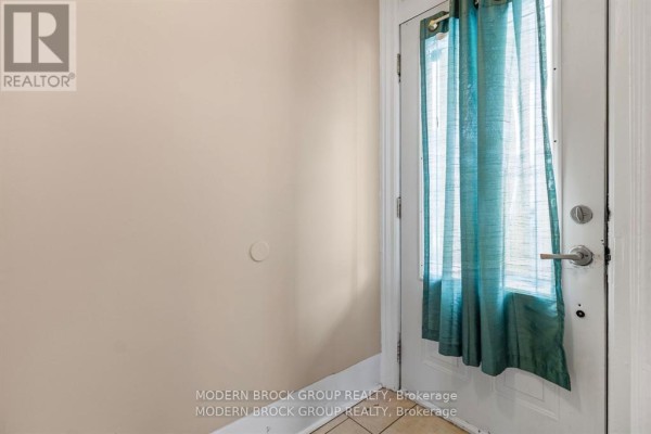 Interior view of a doorway with teal curtains covering a glass-paned door and beige walls. - 96 Brock Street, Brockville