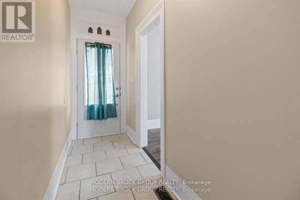 Interior hallway with beige walls, beige tile flooring, and a doorway to another room. - 96 Brock Street, Brockville