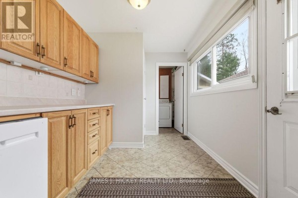 Kitchen area with light oak cabinets, white countertops, and a view into a laundry room with a washing machine. - 96 Glendale Avenue, Deep River