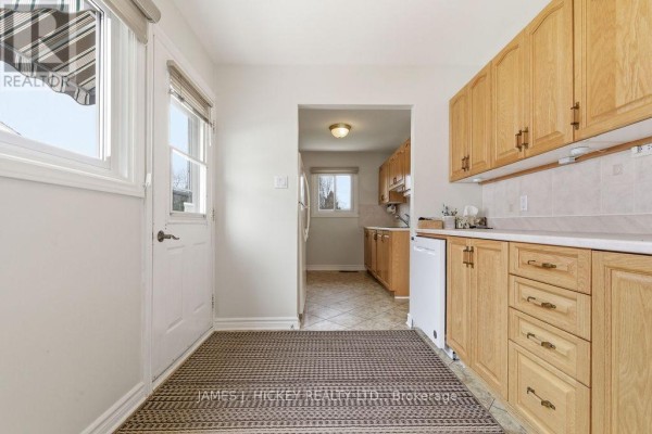 Kitchen with light oak cabinets, white countertop, view of a back door and a window, leading into another room. - 96 Glendale Avenue, Deep River