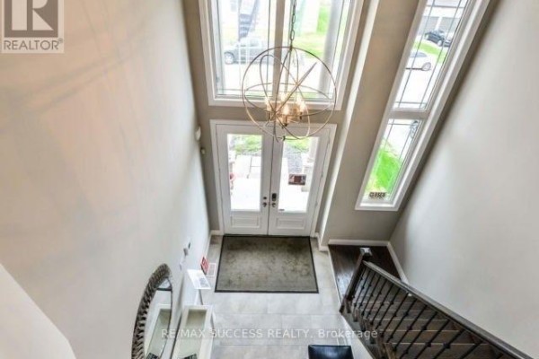 Foyer with double glass doors, tall ceiling, chandelier, and staircase. - 96 Nashville Circle, Hamilton