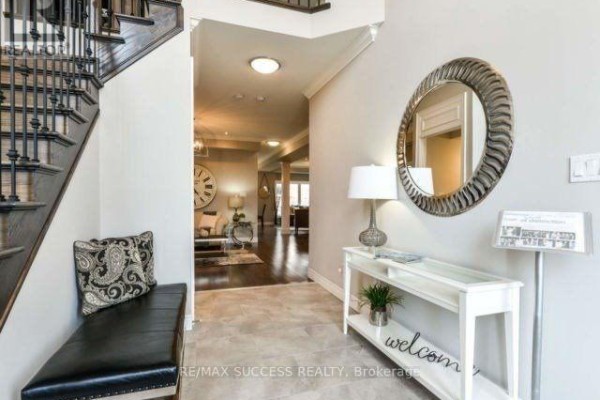 Foyer with tile flooring, a black bench, console table, mirror, and stairs. - 96 Nashville Circle, Hamilton