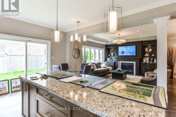Open-concept living area with a fireplace, entertainment unit, large windows, and kitchen island. - 96 Nashville Circle, Hamilton