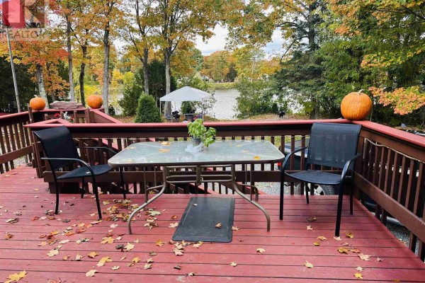 Wooden deck with table, chairs, and fallen leaves, overlooking a calm body of water. - 96 Olar Side Rd, Goulais River