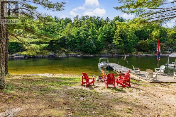 View of the lake from shore with a dock, fire pit, and boat. - 96 Georgian Bay Wa Zone L, Carling