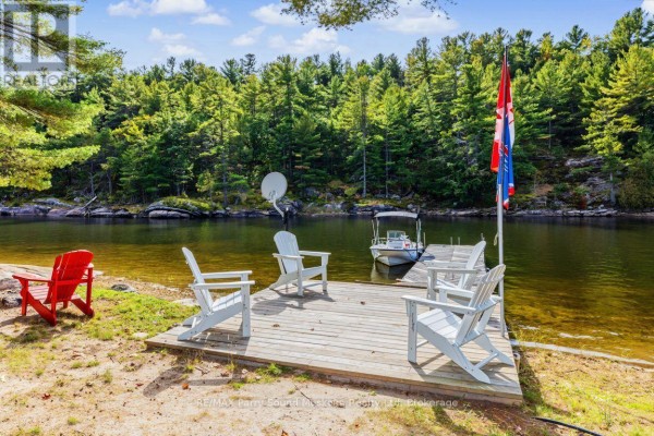 Wooden dock with chairs and a boat on the water. - 96 Georgian Bay Wa Zone L, Carling