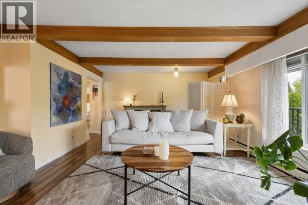 Living room with a white sofa, wooden coffee table, and a large abstract painting on the wall. - 960 Cliff Avenue, Burnaby