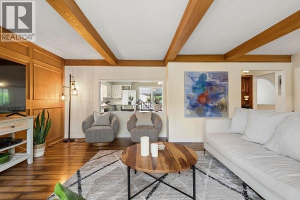Living room with two grey armchairs, a white sofa, and a view into the kitchen. - 960 Cliff Avenue, Burnaby
