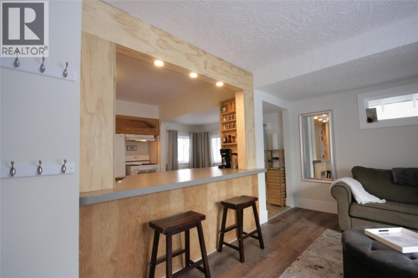 Interior view of a living room and kitchen with a breakfast bar and stools. - 960 Nicola Street, Kamloops