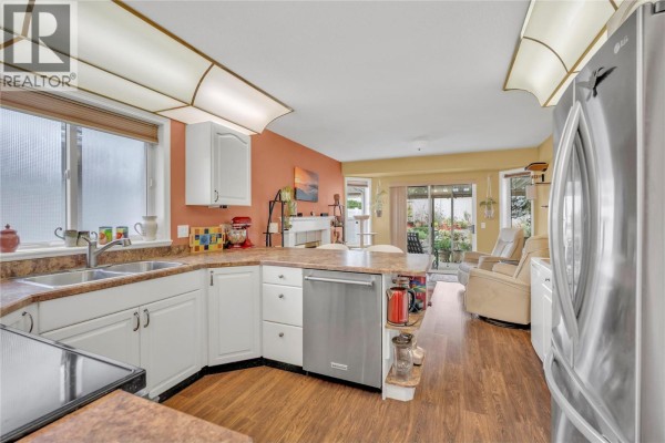 Kitchen with white cabinets, stainless steel appliances, and laminate flooring. - 9600 Turner Street Unit# 20, Summerland