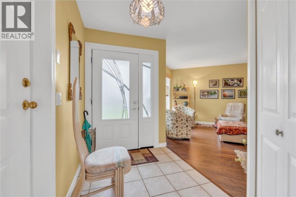 Entrance foyer with tiled floor, white front door, and yellow walls. - 9600 Turner Street Unit# 20, Summerland