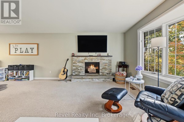 Living room featuring a stone fireplace with a lit fire, television, large windows, and seating area. - 9614 Hwy 63, Unorganized Townships