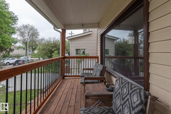 Seating area on the wooden front porch with chairs and a table. - 9623 110a Av Nw, Edmonton
